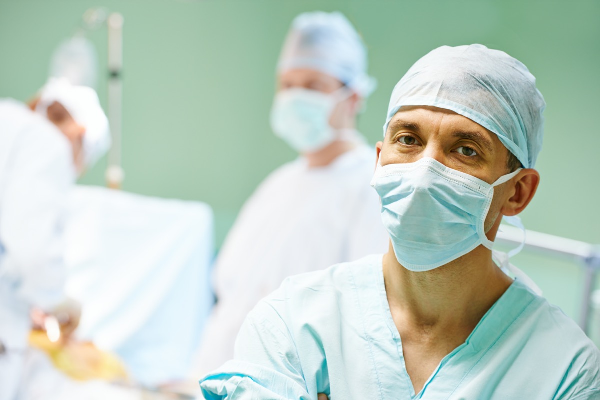 Portrait of surgeon medic in front of surgeons perfoming operation on a patient at cardiac surgery clinic