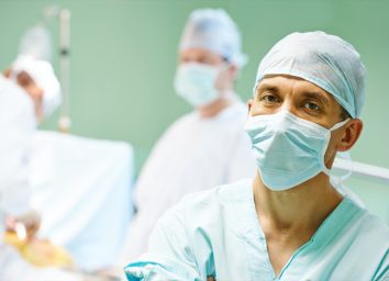 Portrait of surgeon medic in front of surgeons perfoming operation on a patient at cardiac surgery clinic