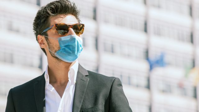 man with surgical face mask and sunglasses outdoors