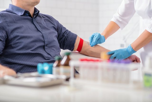 Nurse disinfecting man's arm before blood