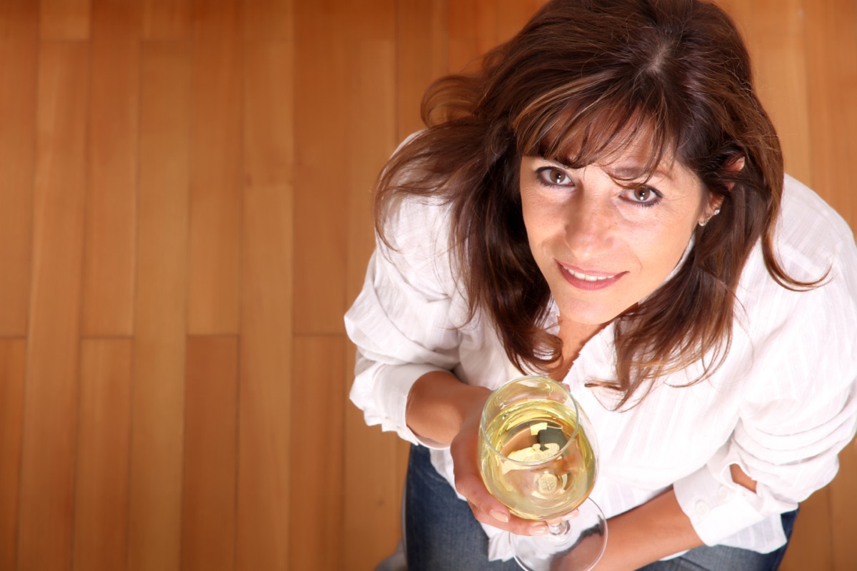 Mature woman with a glass of white wine.