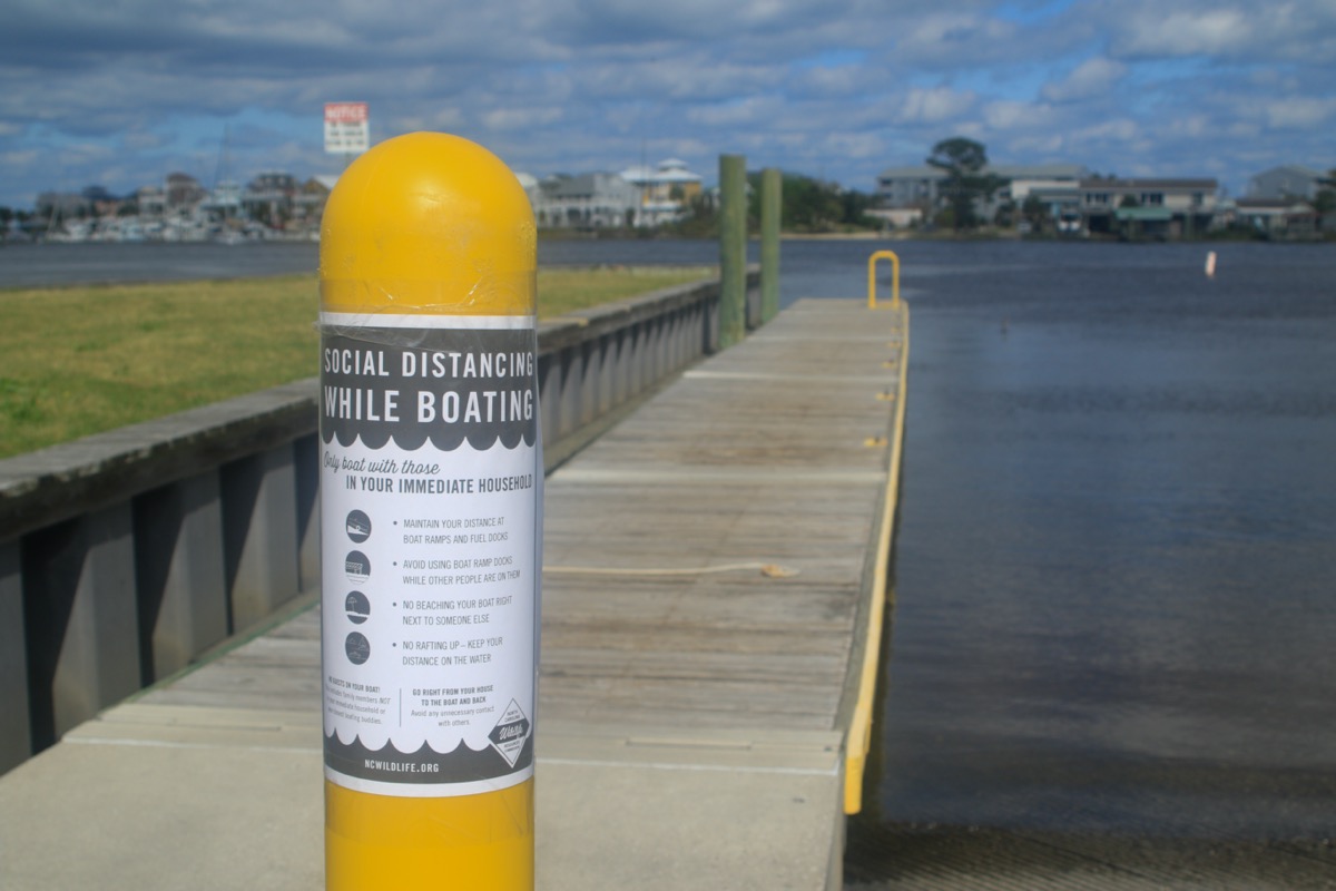 A sign explains social distancing guidelines at a public boat ramp.