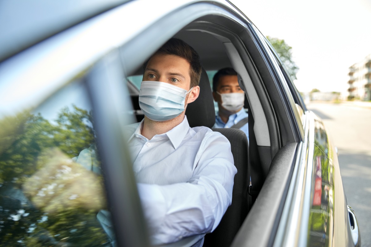male taxi driver wearing face protective medical mask driving car with passenger