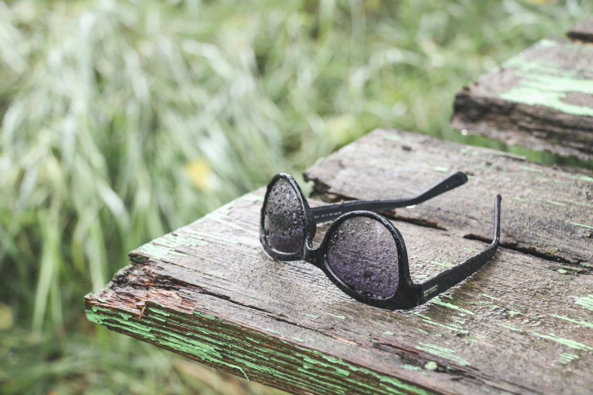 Sunglasses in the rain on old wooden back