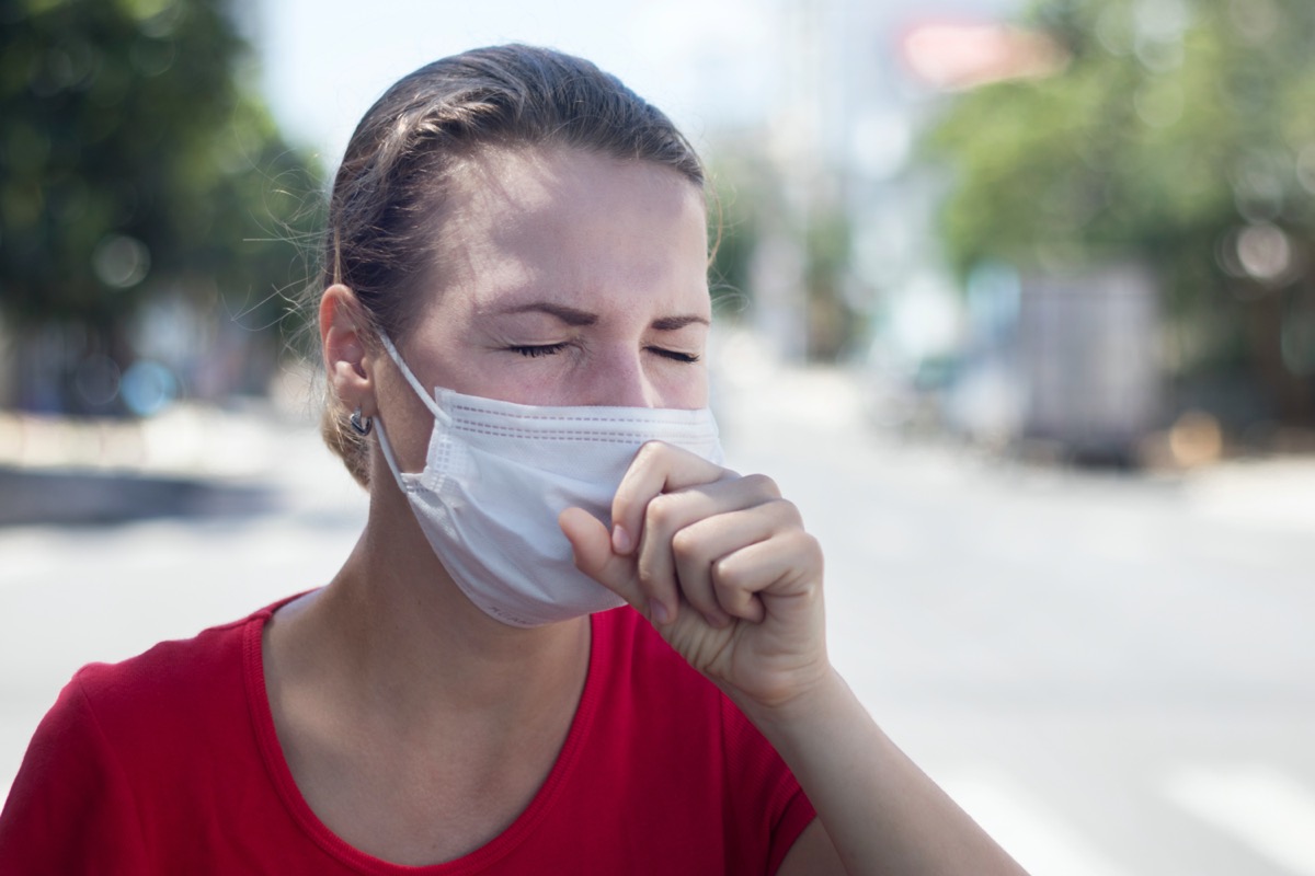woman coughing in medical mask on her face