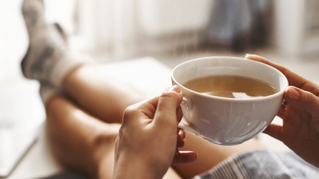 Woman drinking tea relaxing on couch