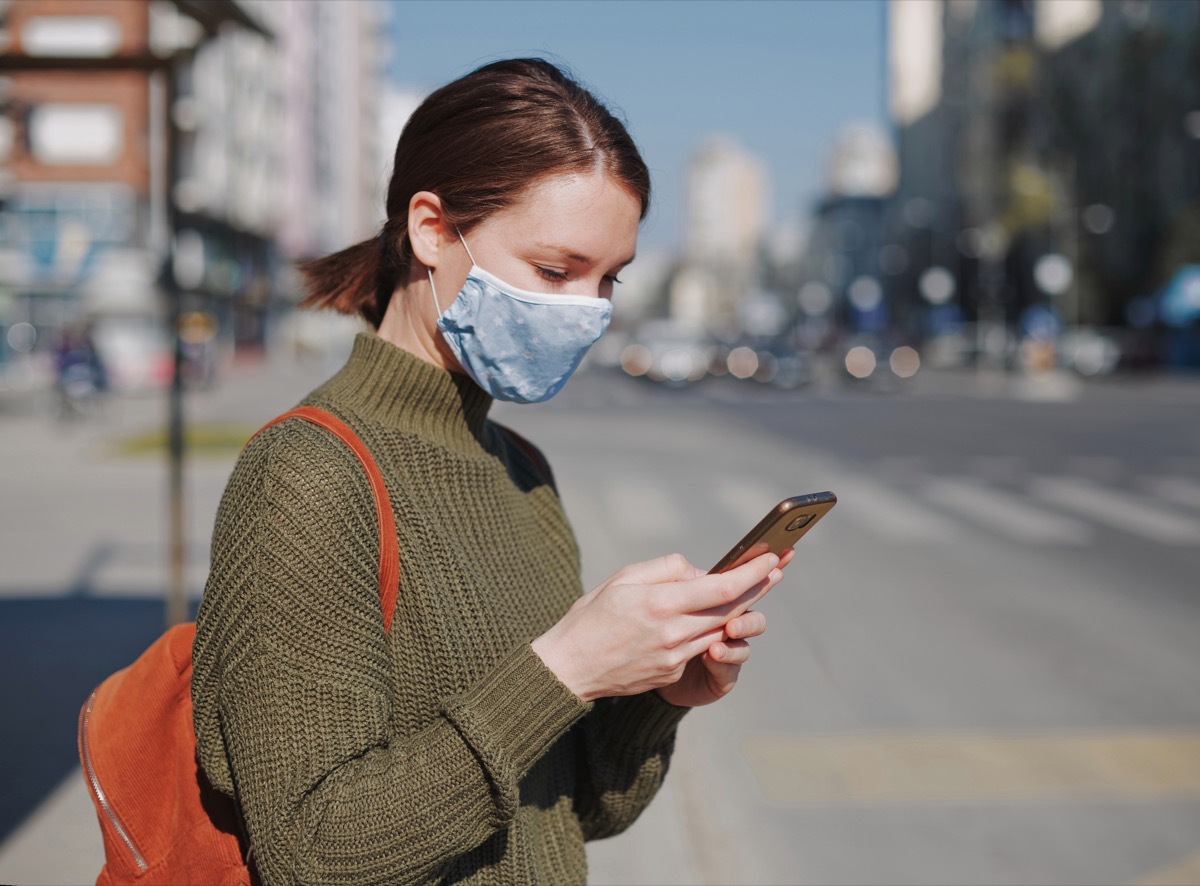 Woman face mask phone checking