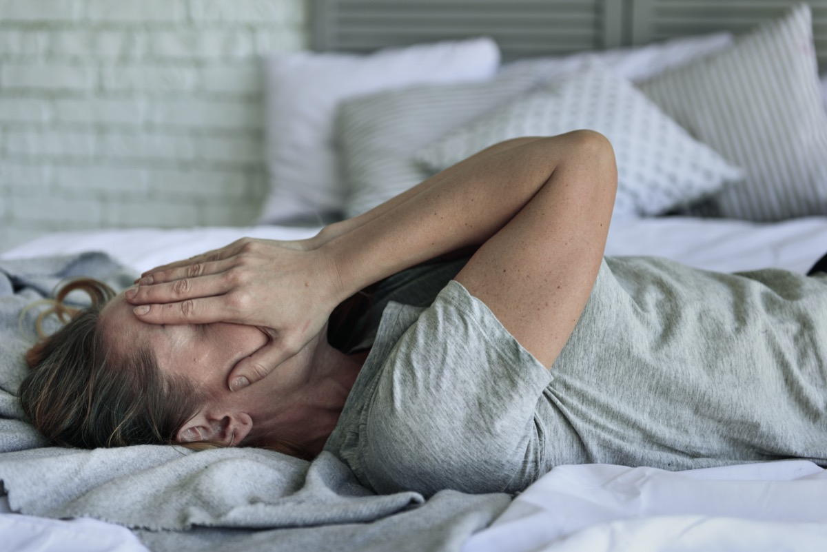 Fatigued woman lying at bedstead