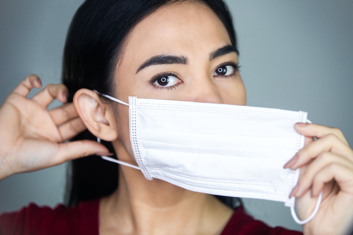 woman putting on a medical disposable mask.
