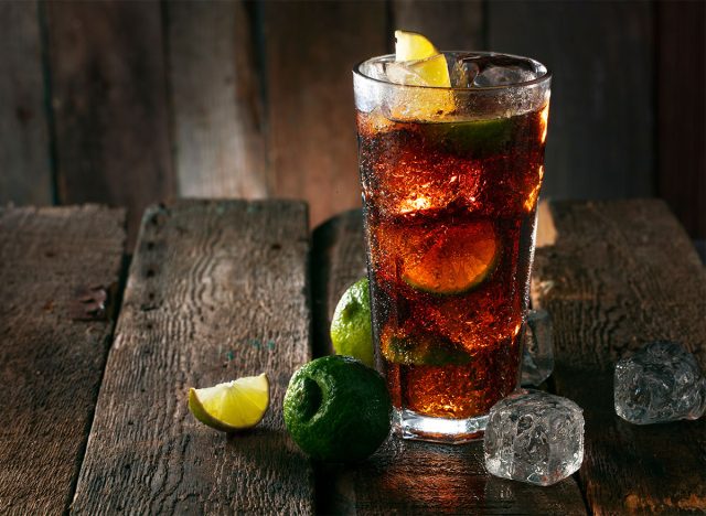 glass of coke with ice and lemon and lime wedges