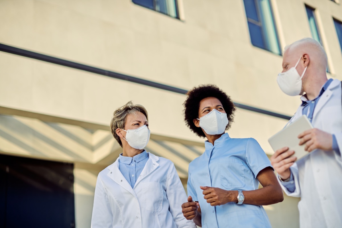 group of doctors talking outdoors while wearing face masks
