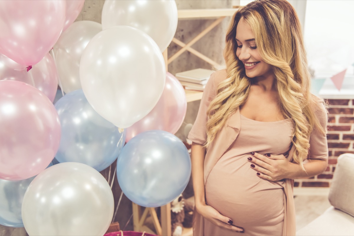 pregnant woman is smoothing her tummy and smiling during baby shower