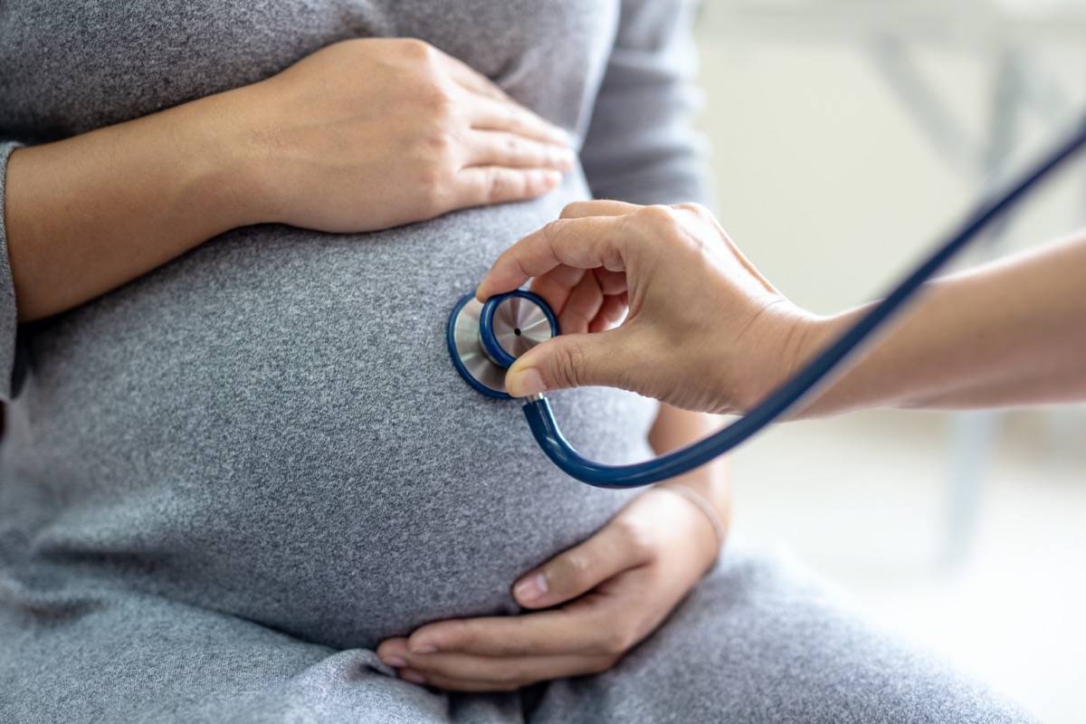 Female doctor is checking pregnant woman with stethoscope