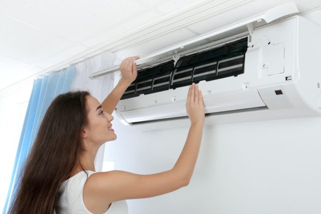 woman checking air conditioner at home