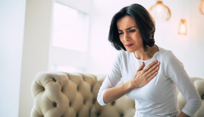 woman who is suffering from a chest pain and touching her heart area
