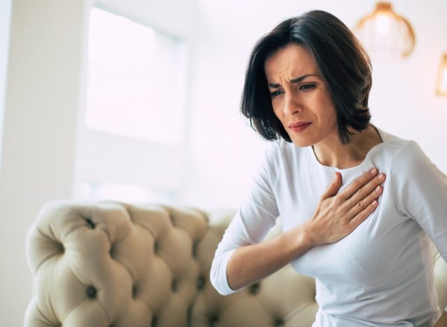 woman who is suffering from a chest pain and touching her heart area