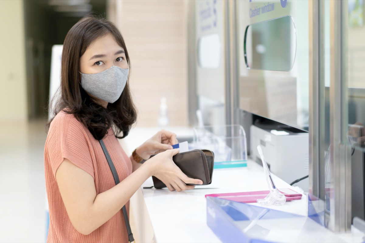 woman with hygiene face mask standing in front of cashier counter in hospital