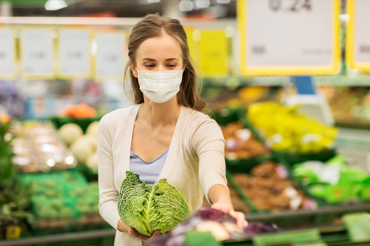 Woman holding cabbage in store.