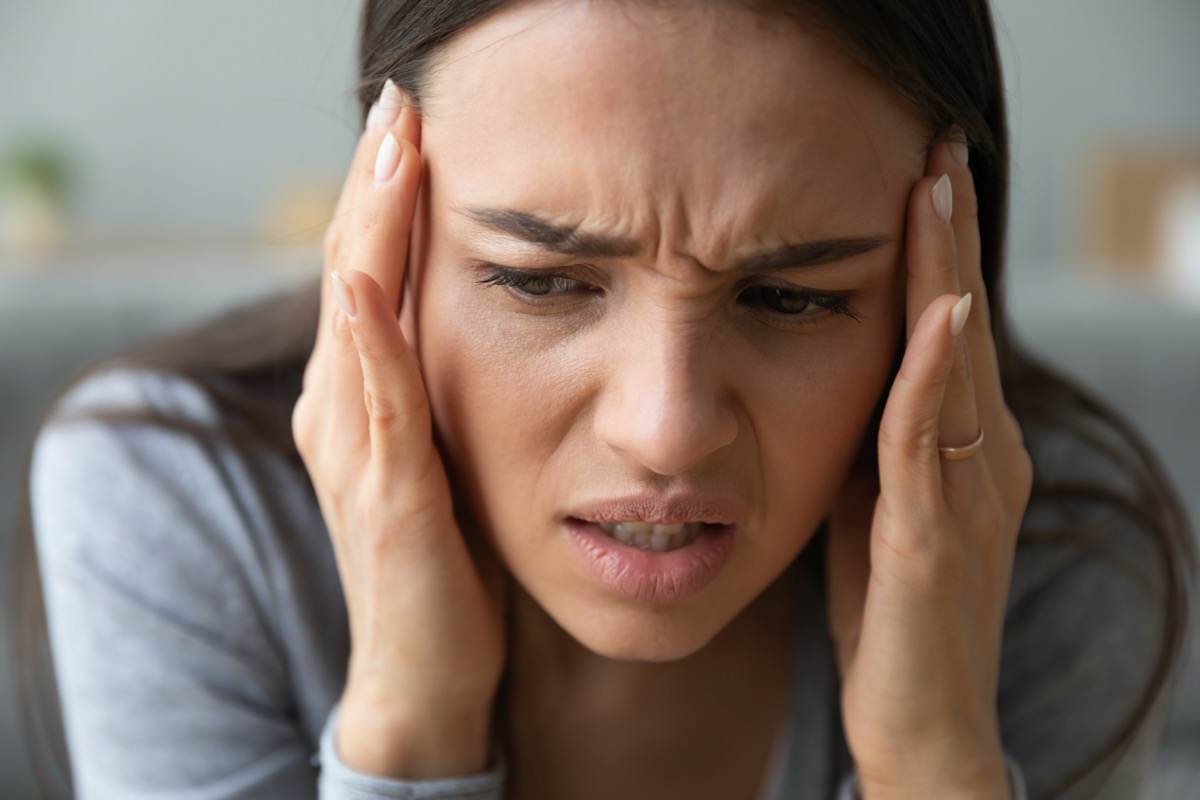Woman touches temples with hands suffers from throbbing severe headache