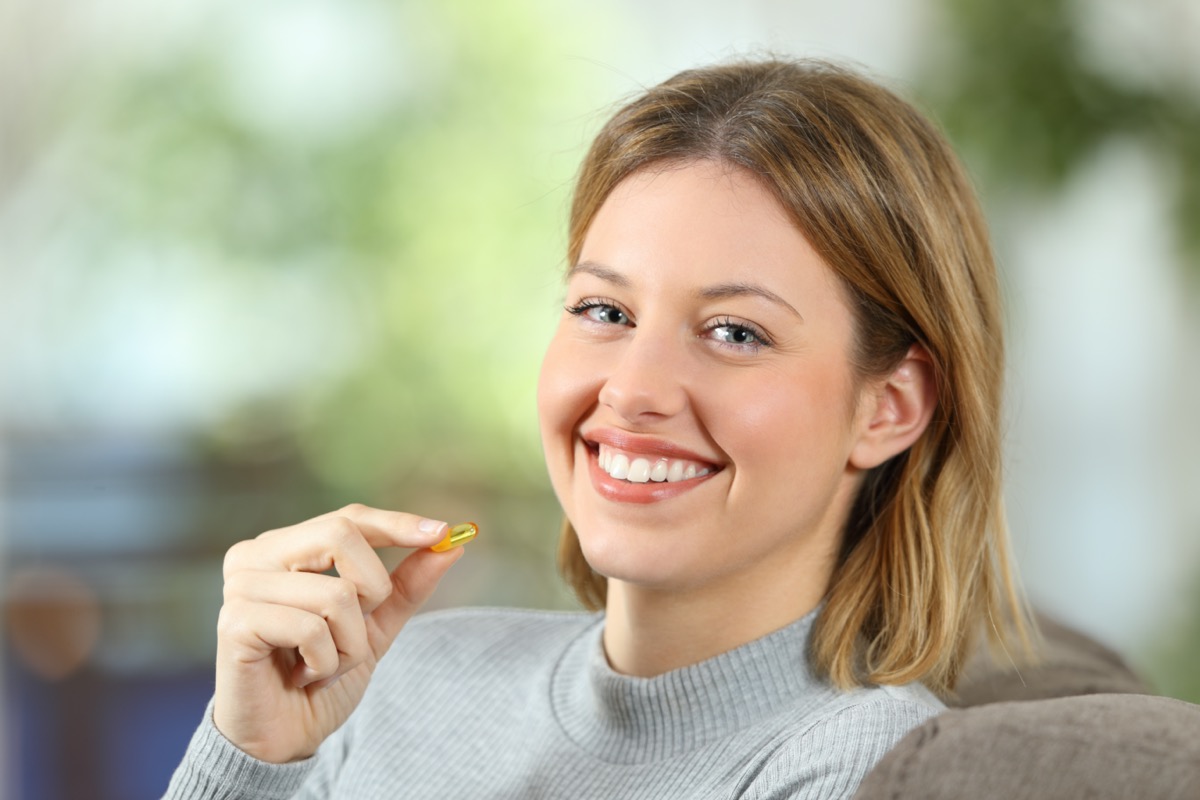 woman holding a vitamin pill