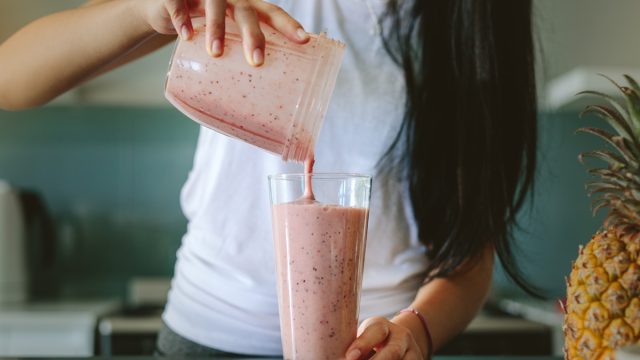 Woman pouring smoothie from blender into a glass