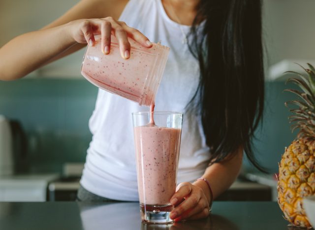 Woman pouring smoothie from blender into a glass