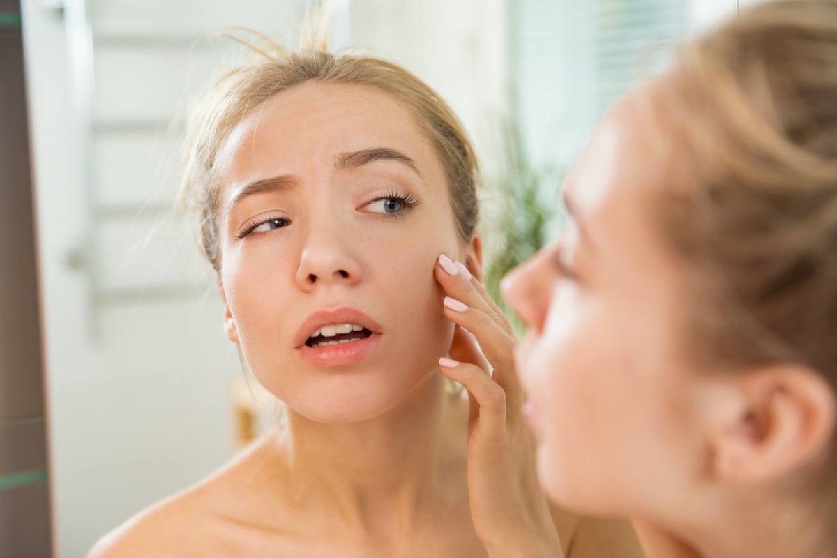 woman touching skin in bathroom