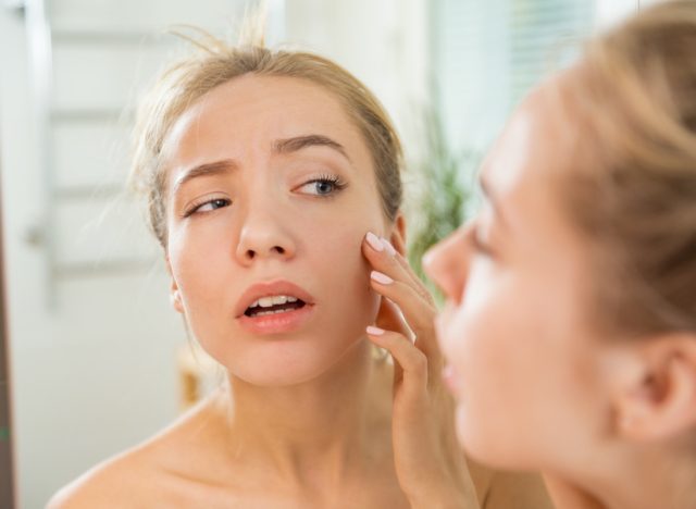 woman touching skin in bathroom