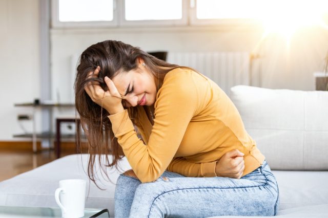 woman with hands holding pressing her crotch lower abdomen