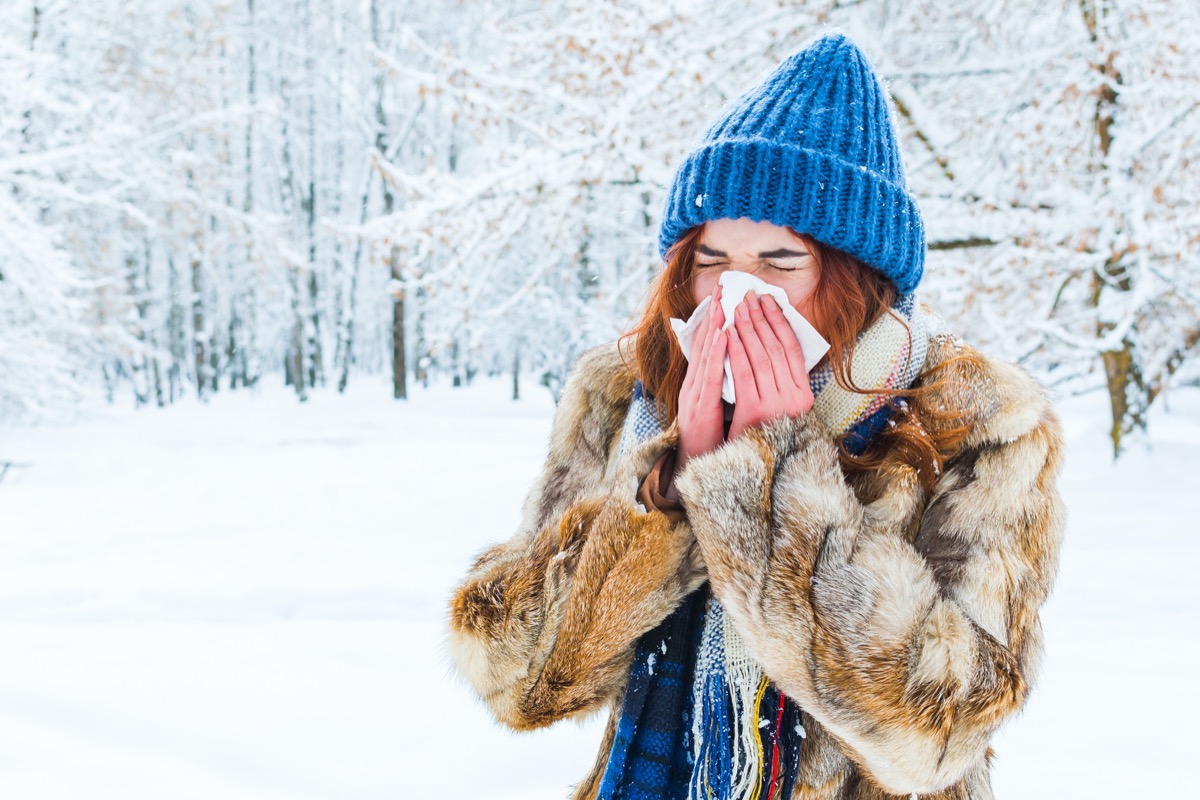 woman in the winter forest. a beautiful girl sneezes into a napkin