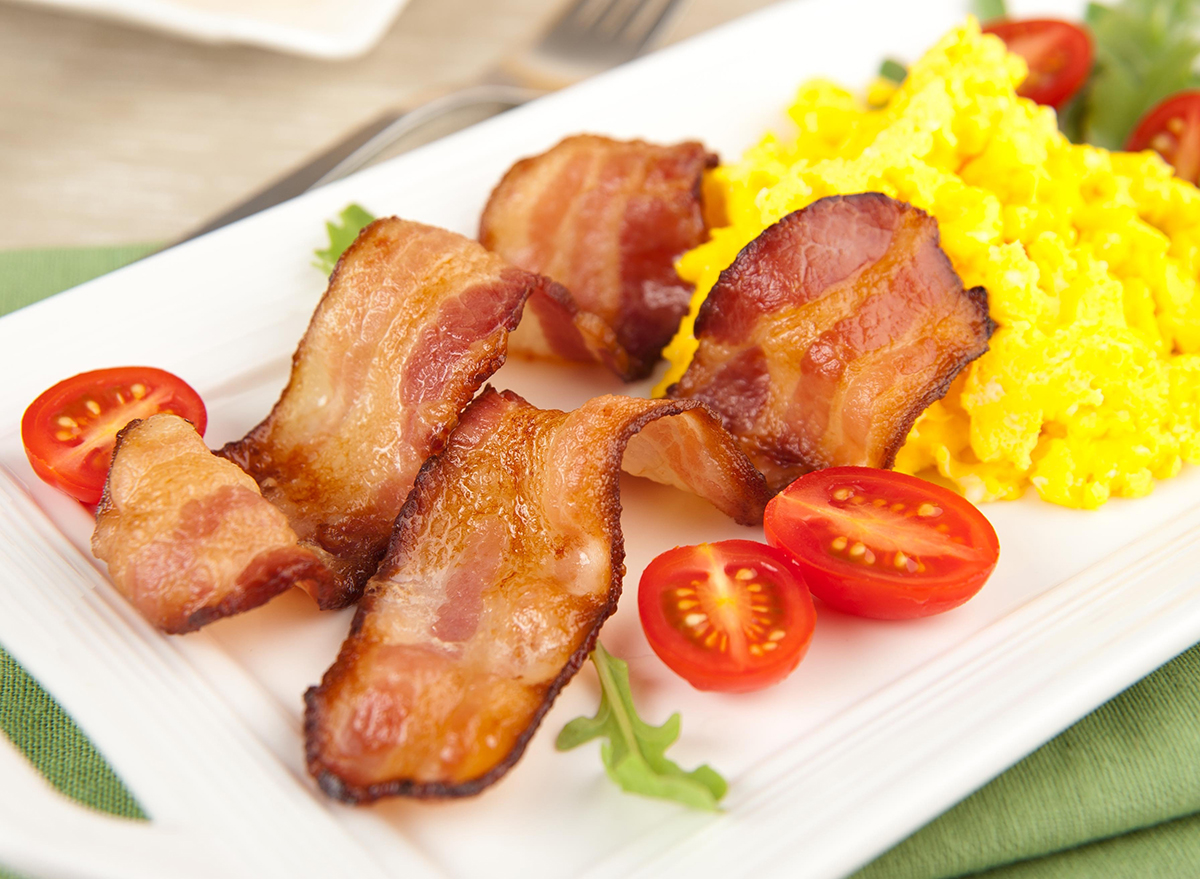 bacon strips with eggs tomatoes and arugula