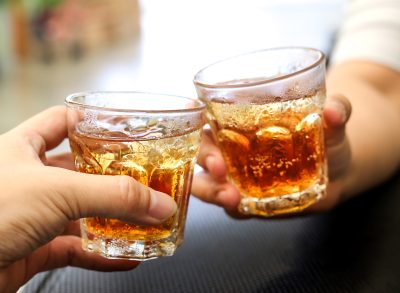 Men cheers with glasses of a whiskey soda alcohol cocktail drink