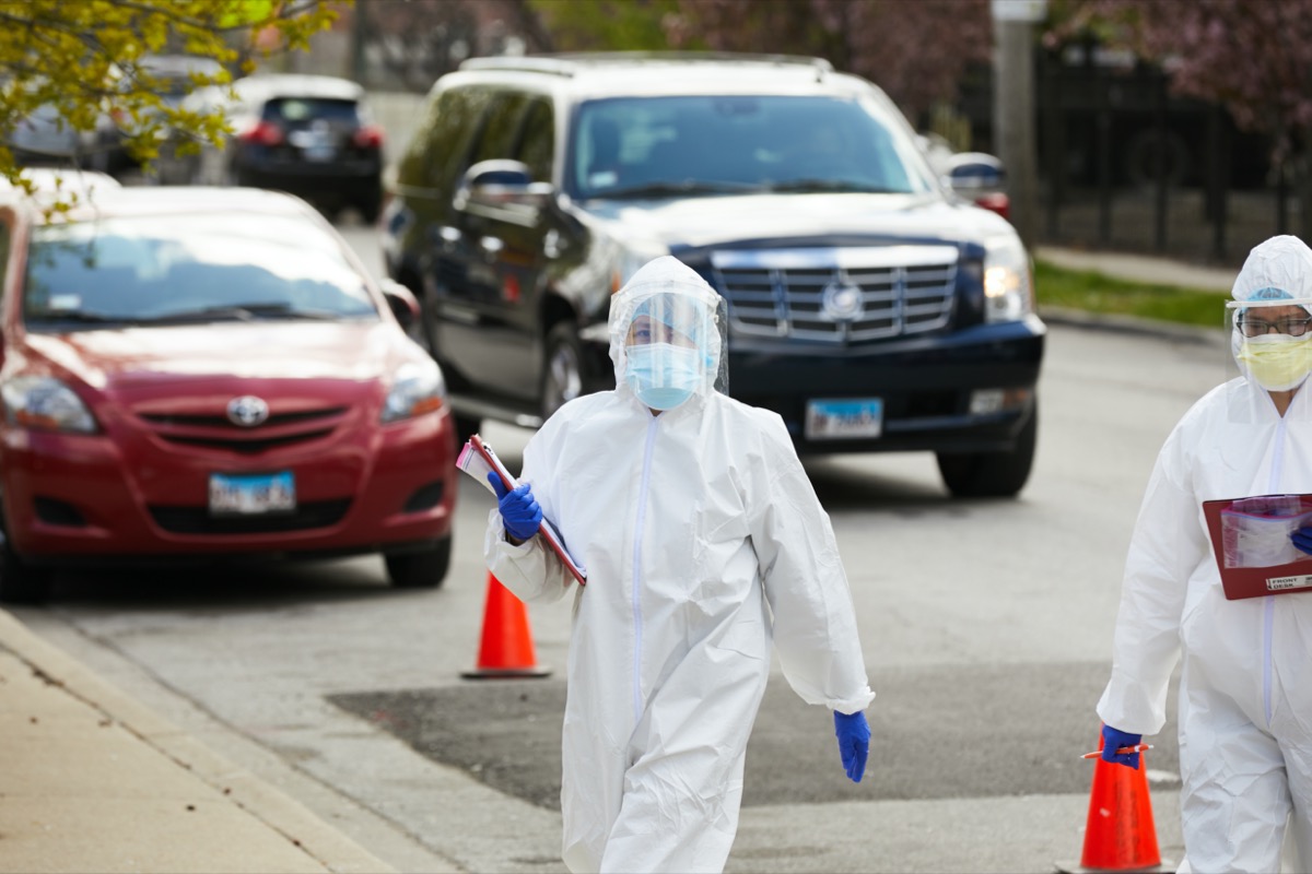 A technician at a drive up testing facility in Chicago walks between cars with patients awaiting testing for coronavirus covid-19