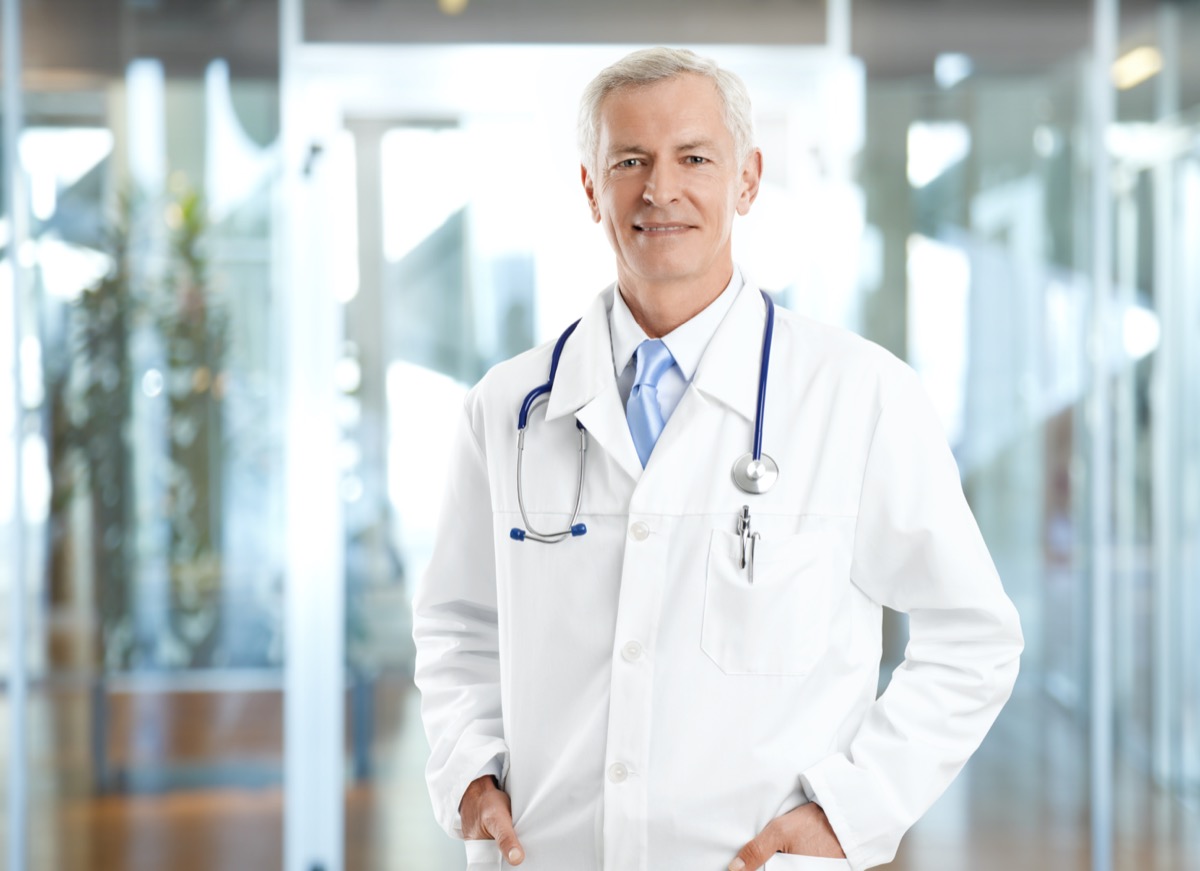 senior male doctor wearing lab coat and standing at private clinic