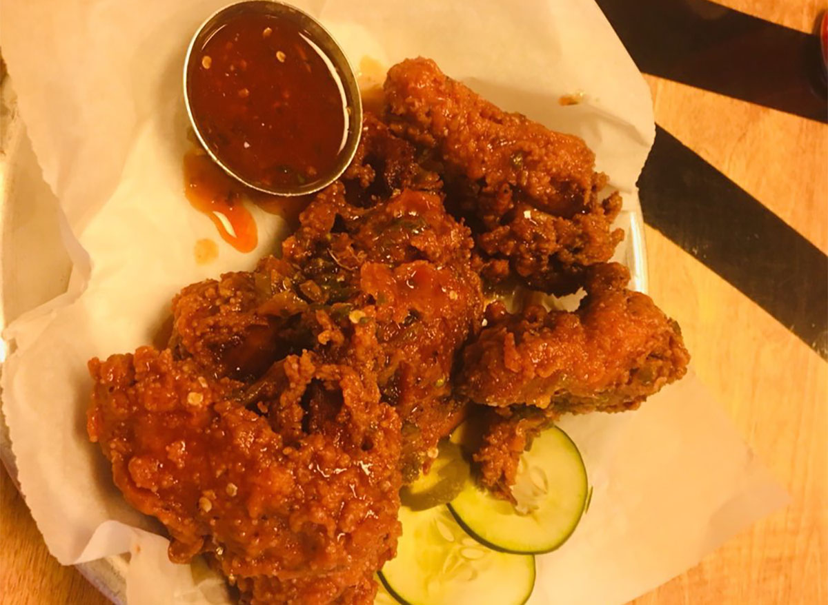 plate of fried chicken with cucumber slices and dipping sauce