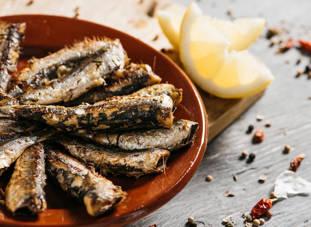grilled sardines on plate with lemon wedge
