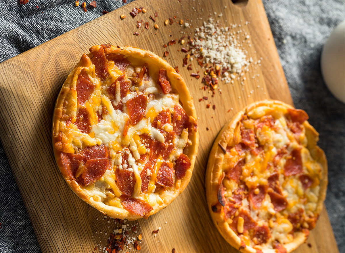 two individual frozen pizzas on wooden board