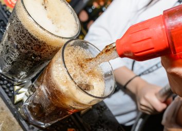 pour soda out of a tap at a bar into an alcoholic cocktail drink