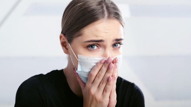sick with a new coronavirus coughs in a disposable facial mask