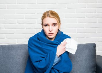Woman Feeling Sick or Sad Wrapped in Cozy Blue Blanket
