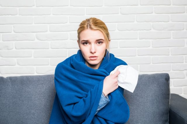 Woman Feeling Sick or Sad Wrapped in Cozy Blue Blanket
