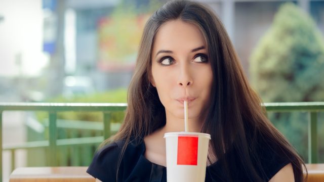 Woman drinking soda trough a straw.