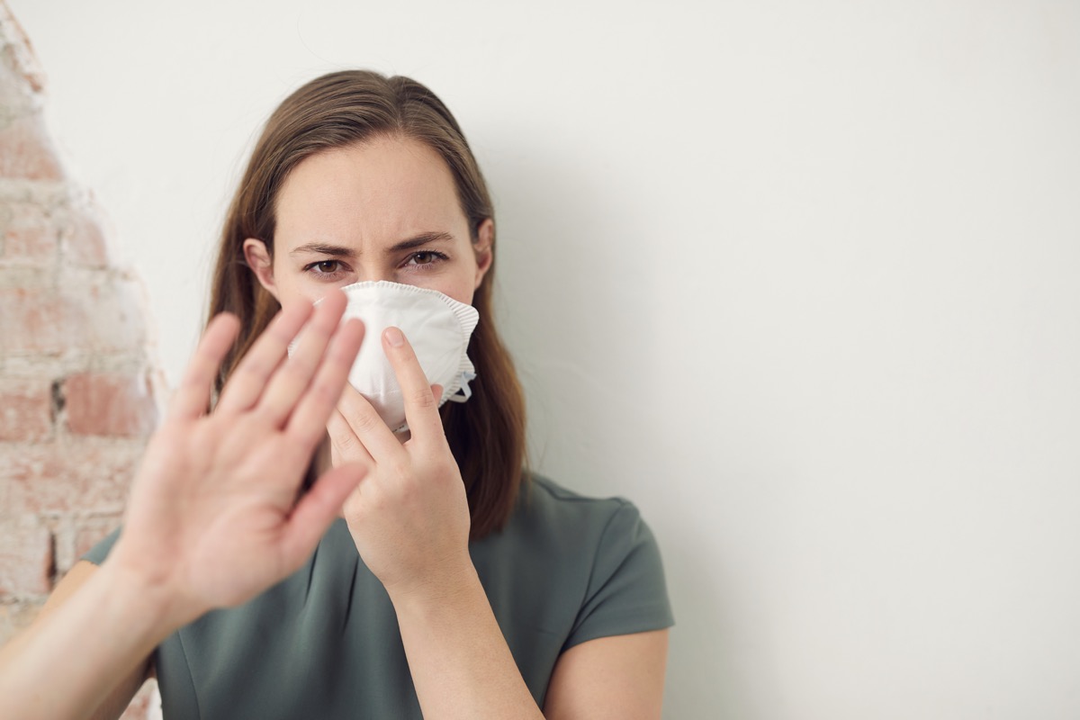 Woman wearing a mask to protect her from virus holding her hand up to stop the virus