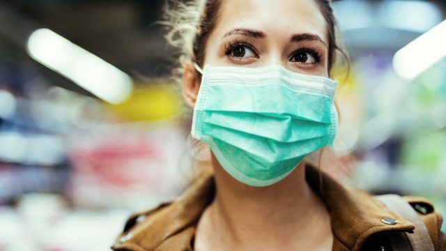 Woman wearing protective mask on her face while being in the store during coronavirus epidemic