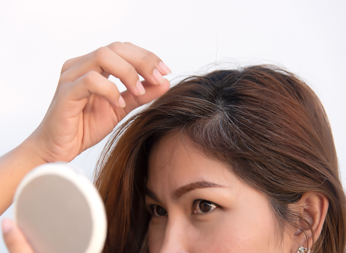 woman looking in mirror finding gray hair