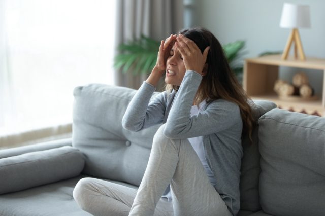 Alnına dokunan, güçlü baş ağrısı veya kronik migren muzdarip stresli mutsuz kadın