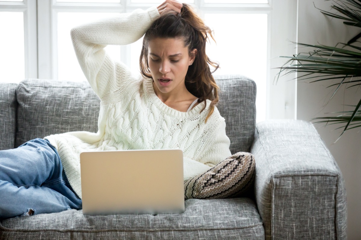 Shocked young woman looking at laptop computer screen at home