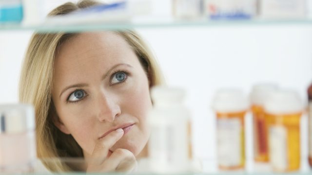 A woman is looking through her medicine cabinet.