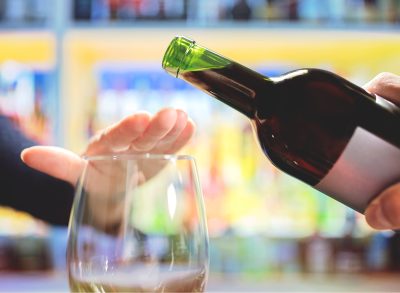 woman refusing or saying no to being poured a glass of wine alcohol