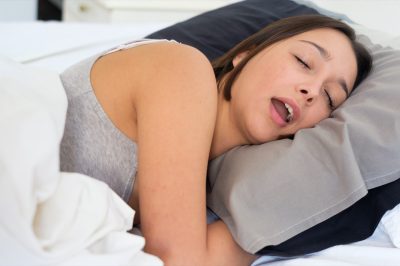 Tired woman snoring loudly in the bed